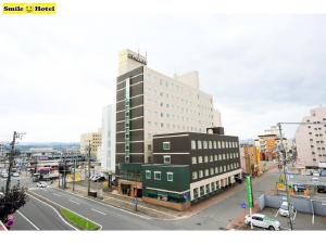 a large building on a city street with a road at Smile Hotel Asahikawa in Asahikawa