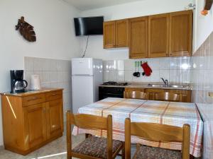 a kitchen with a table and a white refrigerator at Apartmani Danijela Lopar in Lopar