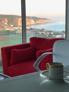 a living room with a red couch and a table with a coffee cup at Le Tableau in Pourville-sur-Mer