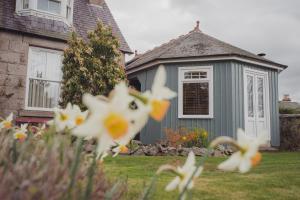 een grijs huis met witte bloemen in de tuin bij Firhurst in Aboyne