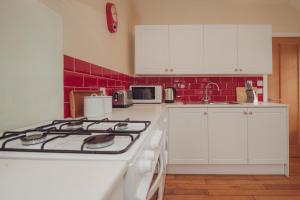 a kitchen with white cabinets and a stove top oven at Firhurst in Aboyne +8 photos