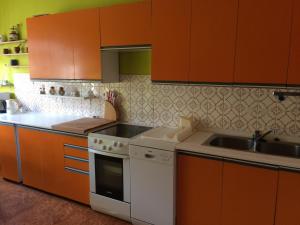 eine Küche mit Orangenschränken, einem weißen Herd und einer Spüle in der Unterkunft Privat Klonga in Smrečany