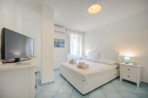 um quarto branco com uma grande cama branca e uma televisão de ecrã plano em Il Poggetto em Ischia