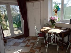 a dining room with a table and chairs and windows at Rosehip Cottage in Somerton