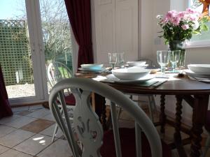 a dining room table with chairs and flowers on it at Rosehip Cottage in Somerton