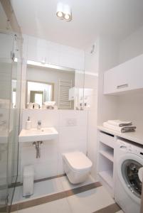 a white bathroom with a toilet and a sink at TLA Kolberg in Kołobrzeg