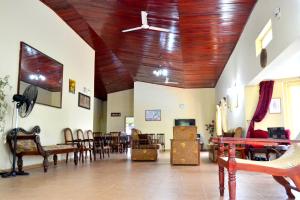 a living room with wooden ceilings and tables and chairs at Sama Uyana Holiday Bungalow in Gampola