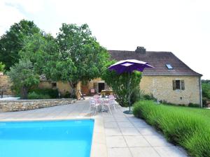 Villefranche-du-PérigordにあるSuperb Holiday Home in Busse with Swimming Poolの紫色のパラソル、テーブル、椅子が備わるパティオ