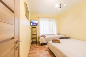 a small room with two beds and a television at Sveciu Namai Alanta in Palanga