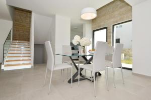 a dining room with a glass table and white chairs at Villa VI in Sevid
