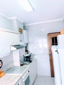 eine Küche mit weißen Schränken und einem weißen Kühlschrank in der Unterkunft Costa Nova Beach View in Gafanha da Encarnação