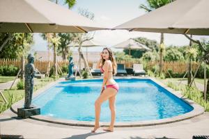 een vrouw in bikini die naast een zwembad staat bij D'Puncak Villas Lembongan in Nusa Lembongan