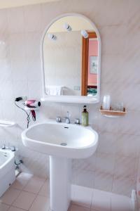 bagno bianco con lavandino e specchio di Hotel Mistral ad Alghero
