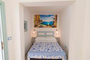 un pequeño dormitorio con una cama y una pintura en la pared en Buon Vento, en Castro di Lecce