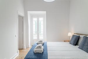 Un dormitorio blanco con una cama con toallas. en Estefânia RoofTop Apartment - Lisbon Center (NEW) en Lisboa