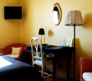 a bedroom with a desk with a lamp and a chair at Hotell Laurentius in Strängnäs