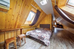 a bedroom with a bed in a wooden house at Gorka Guest House in Lazarevskoye