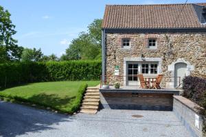 Cette maison en pierre dispose d'une terrasse avec une table et des chaises. dans l'établissement Les houx de Mathieu, à Engis