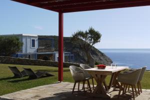 una mesa y sillas en un patio con vistas al océano en Aegea Blue Cycladic Resort, en Zorgos 