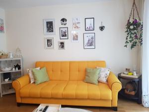a yellow couch in a living room with pictures on the wall at Apartment Georgi Baev in Burgas