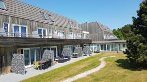 een gebouw met een patio met stoelen en een tafel bij Appartement Senang, Resort Amelander Kaap in Hollum