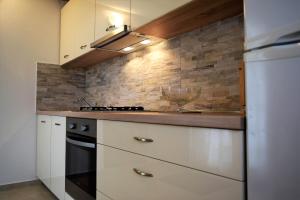 a kitchen with white cabinets and a brick wall at Apartments Kampor in Rab