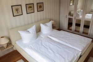 1 cama con sábanas blancas y almohadas en una habitación en Altstadt Ferienwohnungen, en Wernigerode