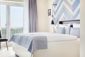 a white bedroom with a bed and a window at Ferienwohnungen Küstenperle in Büsum