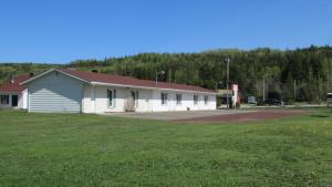 a white building with a red roof in a field at Motel du Bic in Bic