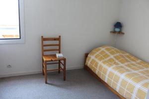 ein Schlafzimmer mit einem Stuhl, einem Bett und einer Lampe in der Unterkunft Maison Saint Hilaire de Riez, 300m de la plage in Saint-Hilaire-de-Riez