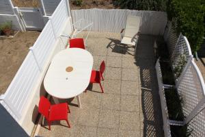 einen weißen Tisch und rote Stühle auf einer Terrasse in der Unterkunft Maison Saint Hilaire de Riez, 300m de la plage in Saint-Hilaire-de-Riez