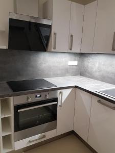 uma cozinha com armários brancos e um forno com placa de fogão em Wellness Apartmány EMPORIO em Loštice