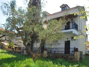 Una casa blanca con un árbol delante. en Red Rose Garden, en Tsilivi