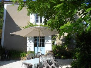 a table and chairs with an umbrella in front of a building at La Cave in Carlux