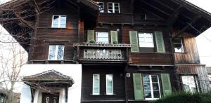 ein altes Haus mit grünen Rollläden und einem Balkon in der Unterkunft Chalet in Bern in Bern
