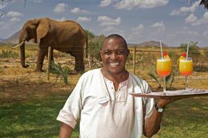 un hombre sosteniendo una bandeja con dos vasos de jugo de naranja en Ashnil Samburu Camp, en Archers Post
