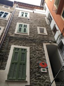 un edificio de piedra con puertas y ventanas verdes en La Torre di Clo B&B, en Dolceacqua