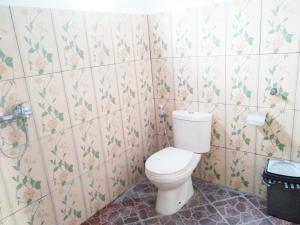 a bathroom with a toilet and flowers on the wall at Yumi House in Ubud