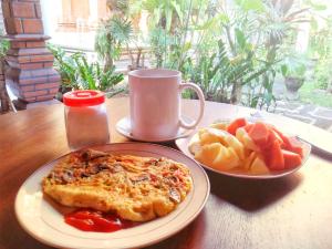 a table with a plate of pizza and a plate of fruit at Yumi House in Ubud +12 photos