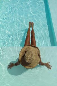 a person in a straw hat laying in a swimming pool at Playa del Mar - Adults Only in Monopoli