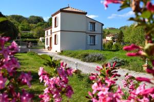 Biały dom z różowymi kwiatami przed nim w obiekcie La Cascadeta w mieście Marignac-Lasclares