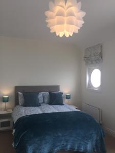 班戈北愛爾蘭的住宿－Luxury house with Sea views，一间卧室配有一张带蓝毯和吊灯的床。