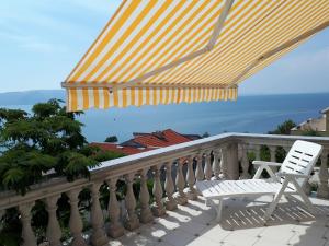 einen weißen Stuhl und einen Regenschirm auf dem Balkon in der Unterkunft Apartments Tomas in Senj