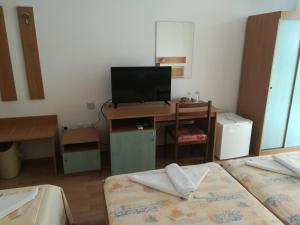 ein Zimmer mit zwei Betten und einem Schreibtisch mit Fernseher in der Unterkunft Hotel Diva in Rawda