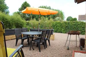 une table et des chaises avec un parasol orange dans l'établissement Chez ma tante, à Méneslies