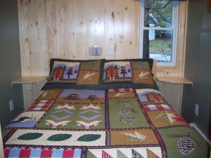 Bett mit einer Decke auf dem Zimmer in der Unterkunft Lakewoods Cottage in Oxtongue Lake