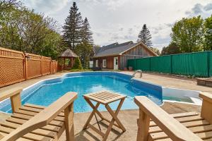 a swimming pool with two chairs and a table at Auberge de la Tour et Spa in Magog-Orford