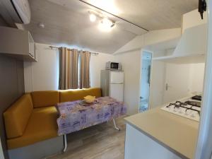 マネルバ・デル・ガルダにあるCamping La Roccaのリビングルーム(黄色のソファ付)、キッチンが備わります。