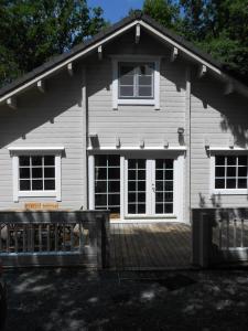 ein weißes Haus mit einer Veranda und einer Holzterrasse in der Unterkunft Chalet Alppimaja in Vesin