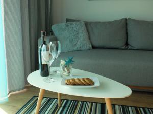 a table with a bottle of wine and a plate of cookies and wine glasses at Apartament 33BalticBlue in Pogorzelica